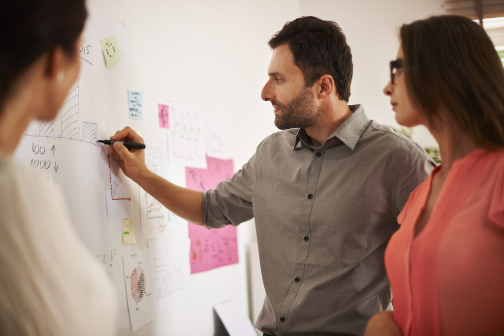 Equipe no trabalho desenhando dados e processos em um quadro branco